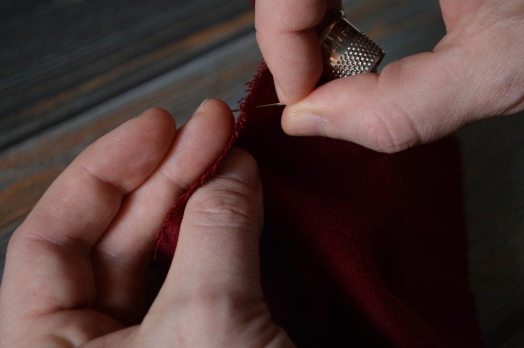 The needle gently pricks the finger on the underside to help gauge the stitch depth.