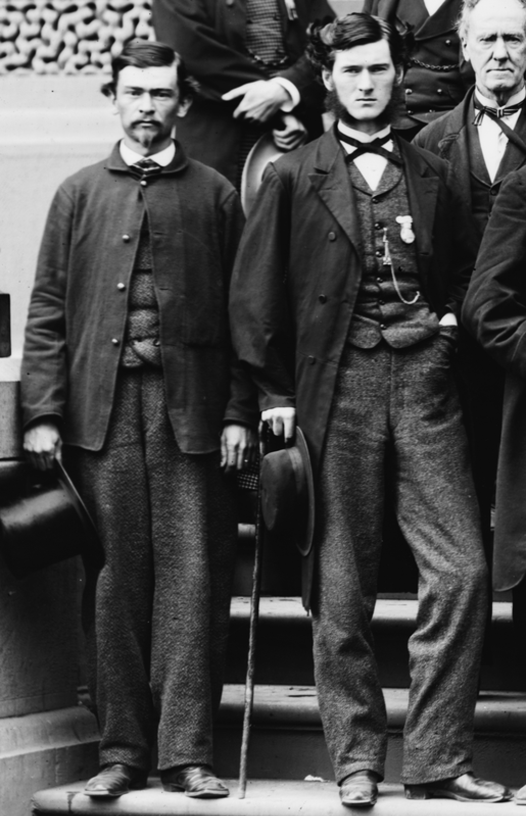 Two gentlemen with matching waistcoats and trousers.
