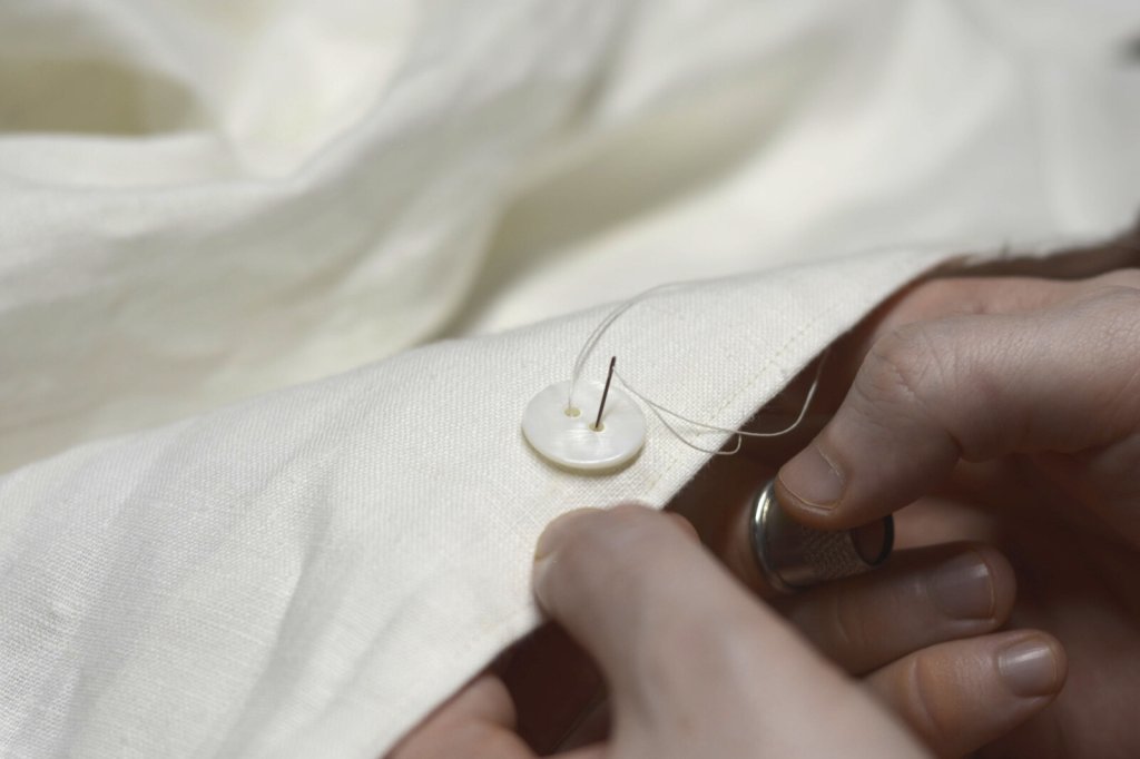 Sewing on a button by hand.