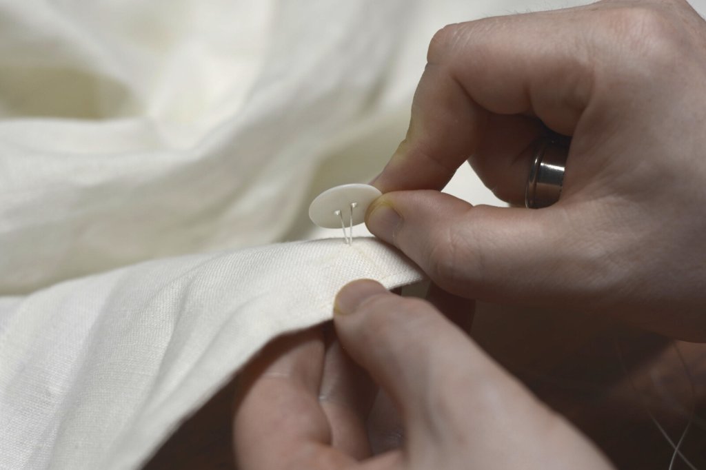 Sewing on a button with hand stitching.