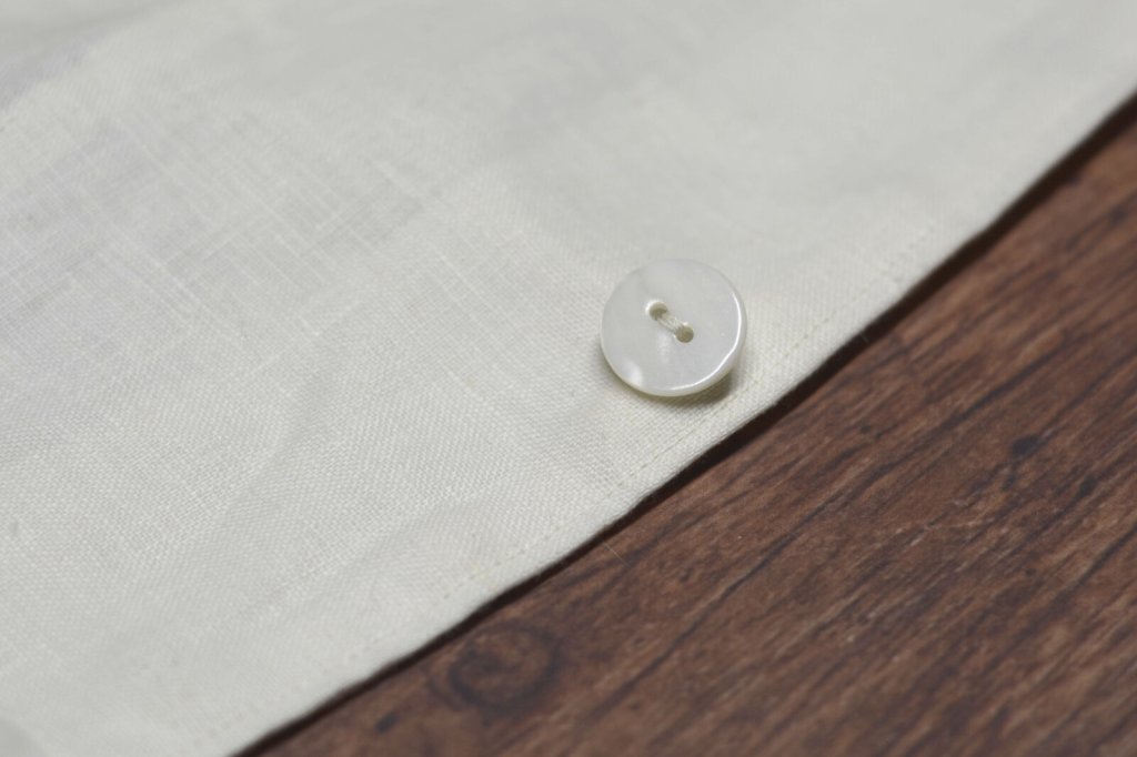A button sewn on white linen fabric.